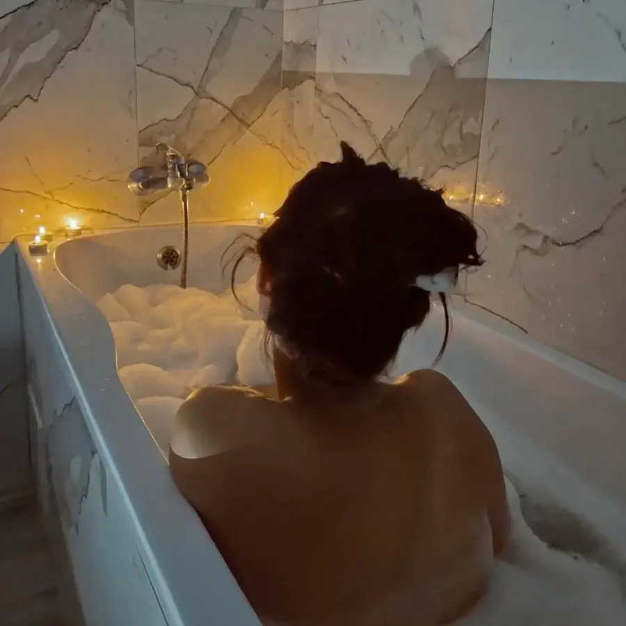 A woman settled into a warm candlelit bath