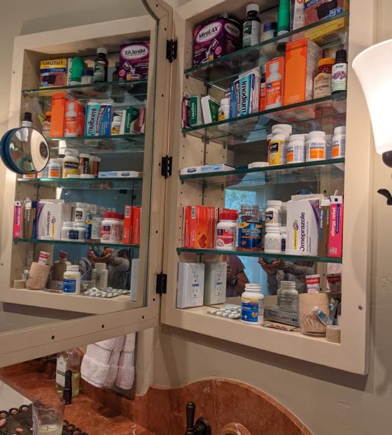 A bathroom cabinet packed with boxes and bottles