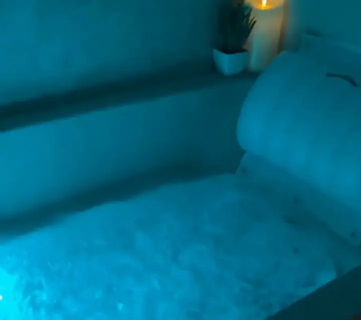 Bath glowing turquoise beside lit candles